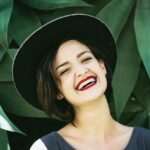 Woman Smiling In Front Of Green Plants