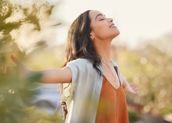 Woman Smiling In Front Of Green Plants